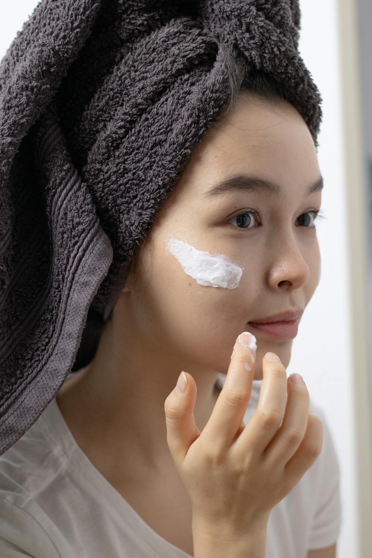 Mujer aplicándose crema hidratante coreana en el rostro para calmar y nutrir la piel sensible