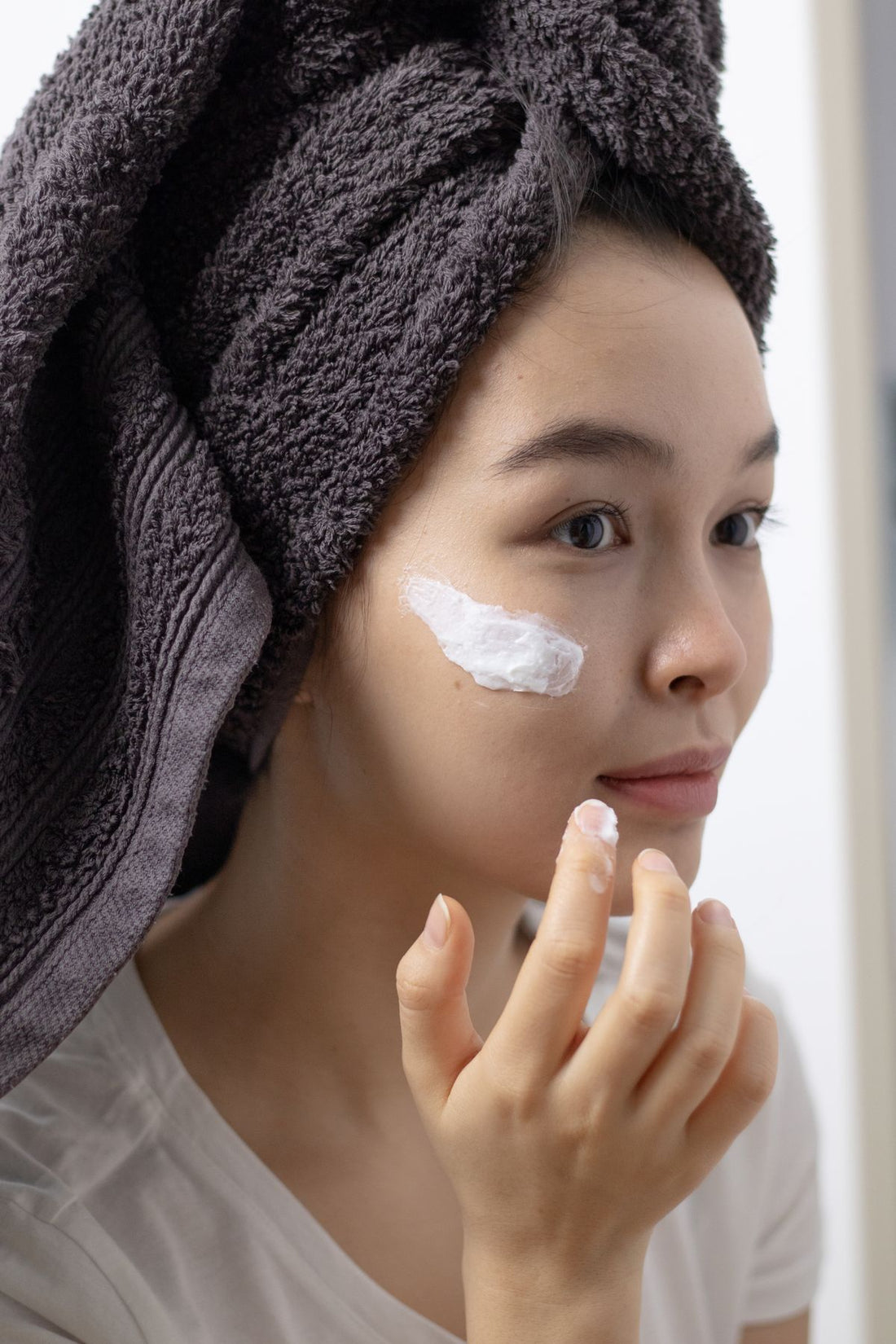Close-up of a woman applying a cleanser to her face, illustrating the steps of a Korean double cleansing routine